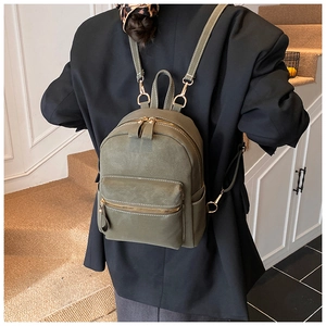 Close-up of army green mini backpack featuring gold zippers and matte leather texture