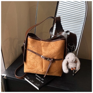 Detail of camel bucket bag with brown trim and cute white plush bunny charm