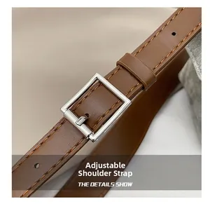 Gros plan d'une bandoulière réglable en cuir marron avec une boucle en métal argenté fin