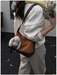 Detail of a large capacity canvas hobo bag in autumn tones with a cute bunny charm