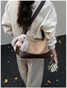 Detail of hobo bag with contrast colors and cute plush rabbit charm in an outdoor setting