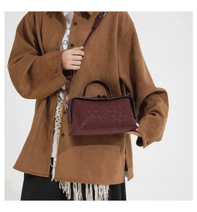 Detail view of burgundy leopard print handbag worn with a brown suede jacket