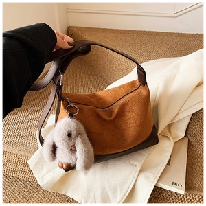 Detail of brown pleated shoulder bag with smooth leather trim and cute rabbit pendant