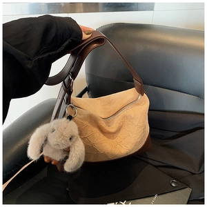 Close-up of beige pleated shoulder bag with dark brown leather trim and cute bunny charm