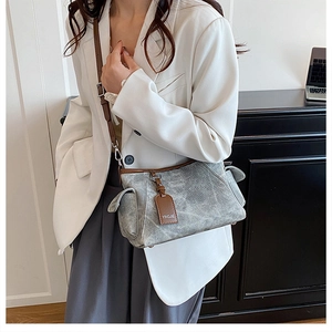 Détail d'un sac à bandoulière rétro gris délavé avec finitions cuir brun et poches à rabat