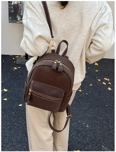 Detail of dark brown minimalist backpack with contrast white stitching and gold hardware