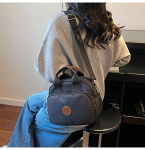 Detail of black fabric crossbody bag with round brown patch on model back