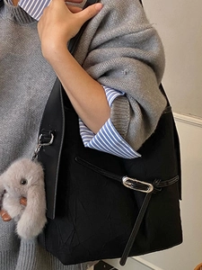 Minimalist black pleated bucket bag with plush rabbit charm and silver metal hardware