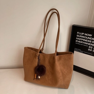 Detail of camel tote bag featuring matte leather texture and colorful beaded tassel charm