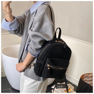 Detail view of black backpack with white contrast stitching and gold metal hardware