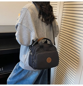 Detail view of stylish black crossbody square bag showing zipper pockets and texture
