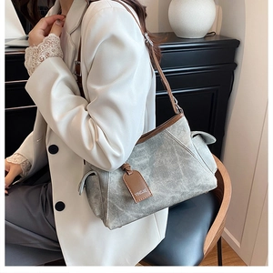 Détail du sac à bandoulière gris avec bordure en cuir marron et poche latérale