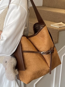 Fashionable textured bucket bag in brown orange with dark straps and plush charm