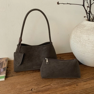 Retro dark brown suede handbag set with fashion logo on vintage wooden surface