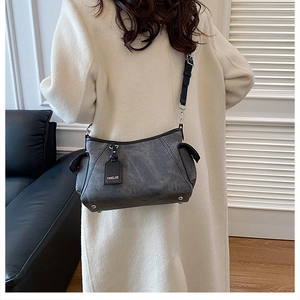 Détail du sac à bandoulière gris rétro montrant la texture cuir et le pendentif