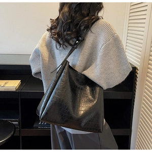 Detailed texture of black crocodile embossed leather on a large shoulder bucket bag