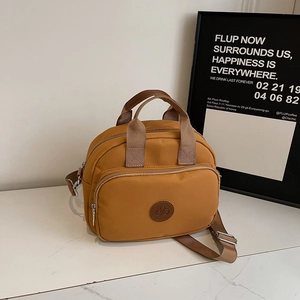 Detail view of ginger yellow nylon crossbody bag with silver hardware and dual handles