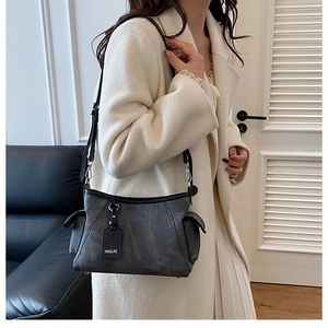 Détail du sac à bandoulière en cuir gris foncé avec poche latérale et crochet argenté