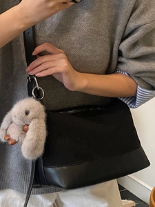Minimalist black canvas shoulder bag with adjustable strap and grey plush bunny charm