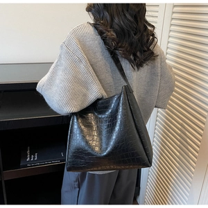 Detail of black crocodile pattern leather tote bag shown from a stylish side view profile