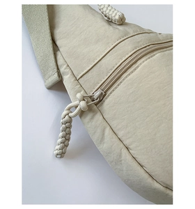 Close-up of beige tote bag fabric showing woven cord zipper pull and durable strap