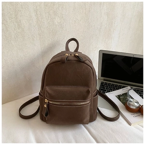 Detail of dark brown mini backpack with contrast stitching and golden zipper hardware