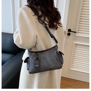 Détail du sac bandoulière gris délavé avec sangle réglable et poches latérales sur manteau