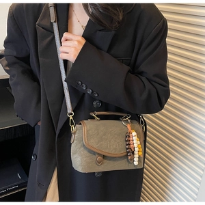 Close-up of vintage olive crossbody bag with brown trim and colorful bead accessory