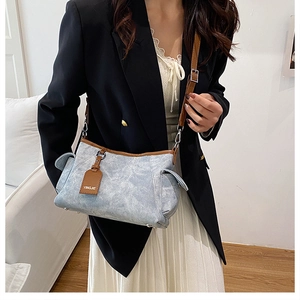 Détail du sac à bandoulière bleu à motif marbré avec bordure en cuir marron et poche
