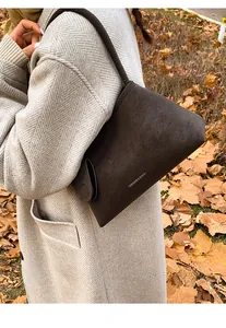 Detail of vintage brown suede handbag with gold lettering in an autumn street setting