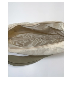 Interior view of beige nylon tote bag with inner pocket and green woven strap