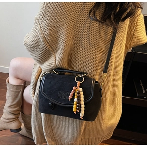 Detail of black crossbody bag featuring MICKEY MONSTERS lettering and beaded tassel charm