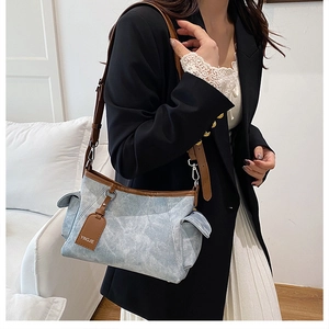 Détail du sac à bandoulière à motif marbré bleu clair avec lanières en cuir brun et boucle métal