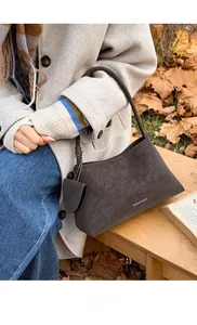Detail of suede crescent shoulder bag in dark grey with matching mini coin purse hanging