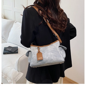 Détail du sac bandoulière en toile grise avec garniture en cuir brun et poche