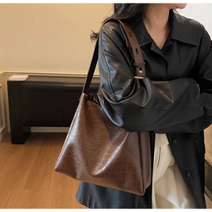 Detail of vintage dark brown tote bag featuring embossed crocodile pattern and wide strap