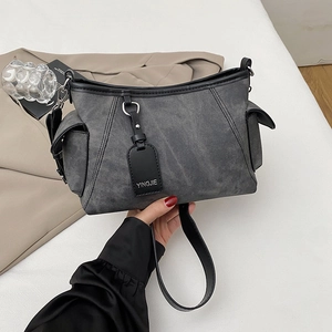 Détail du sac à bandoulière en toile gris anthracite avec poches latérales et bordure en cuir