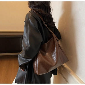 Detailed side view of dark brown croc-embossed hobo shoulder bag worn by model