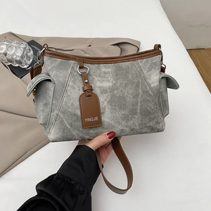 Détail du sac à bandoulière en toile grise avec finitions en cuir brun et poches