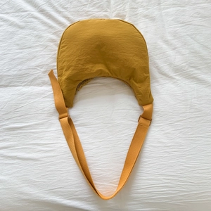 Detail view of the ginger yellow nylon crescent bag with adjustable strap and textured fabric