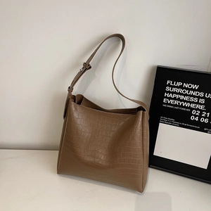 Detailed view of brown crocodile pattern texture and silver buckle on tote bag