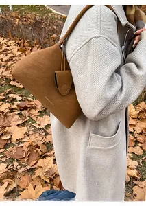 Detail of a brown vintage suede shoulder bag with gold lettering and decorative hang tag