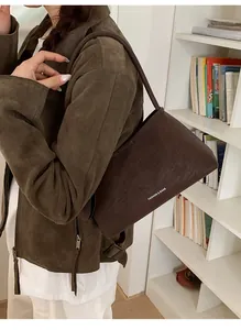 Detail of dark brown suede shoulder bag with 'FASHION & BAGS' text on the front