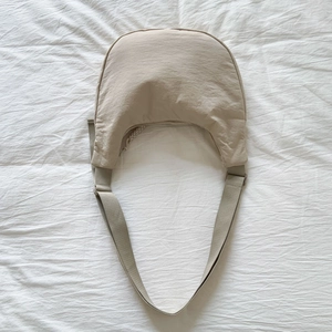 Detail of beige crescent crossbody bag showing water-resistant nylon fabric and strap