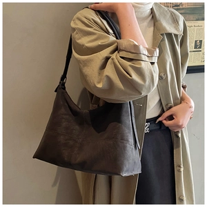 Detail view of charcoal grey suede tote bag with cross-stitch pattern and adjustable strap