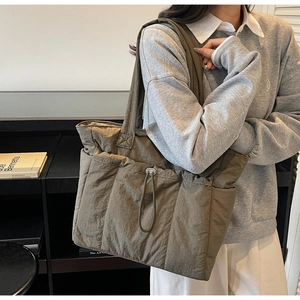 Detail of olive nylon tote bag featuring drawstring pockets and quilted texture