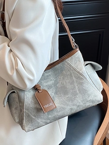 Sac à épaule minimaliste en cuir gris avec bordure marron porté par un mannequin