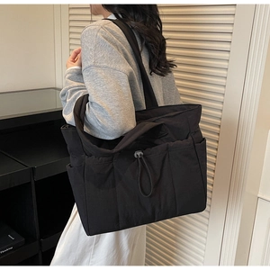 Detail of a large black nylon tote bag with multiple pockets and drawstring buckle
