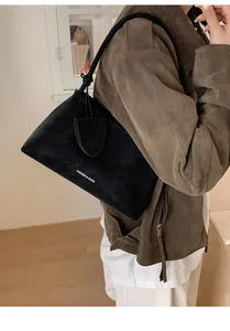 Detailed side view of the black suede tote bag showing the texture and logo lettering