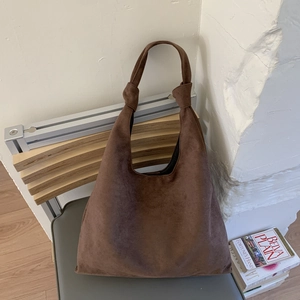Detail showing high-capacity suede hobo bag with unique knotted handle design and soft texture